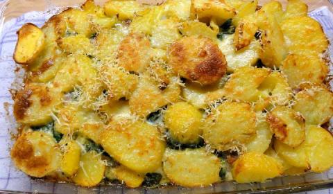 Zapečené brambory se špenátem a uzeným masem posypané sýrem.