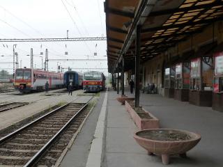 Pojedeme-li vlakem, cestujeme nejdřív do Budapešti na nádraží Keleti (Východní, rychlíky od Slovenska na ně přijíždějí) a na něm přestoupíme na vlak směr Békéscsaba. Budeme-li mít trochu víc času, nádraží si prohlédneme, je zajímavé, historické, neprůjezdné. Není třeba používat podchodů, což ocení lidé s kufry. Békéscsabu není možno přejet, je to velké nádraží a vlak tam obvykle pár minut stojí.