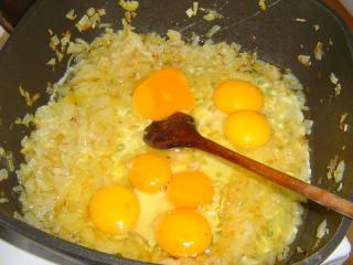 Vrátíme se k cibulce. Kastrol můžeme přemístit na horkou plotýnku, kde se vařily knedlíky. Zahřejeme tuk a na cibulku vlijeme syrová vajíčka. Je lepší jedno každé rozklepnout nad „kontrolní“ miskou, abychom případně včas eliminovali vejce špatné a nezkazili si jím všechny ostatní suroviny. Na jednu porci počítáme jedno až dvě vejce – podle toho, jak vzácná nám vajíčka jsou. Mírně osolíme a usmažíme, mohou být i tužší.
